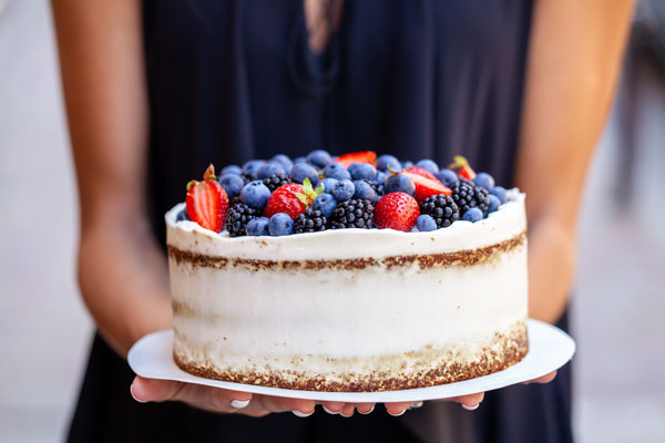 Woman in blue dress holding a berry cake