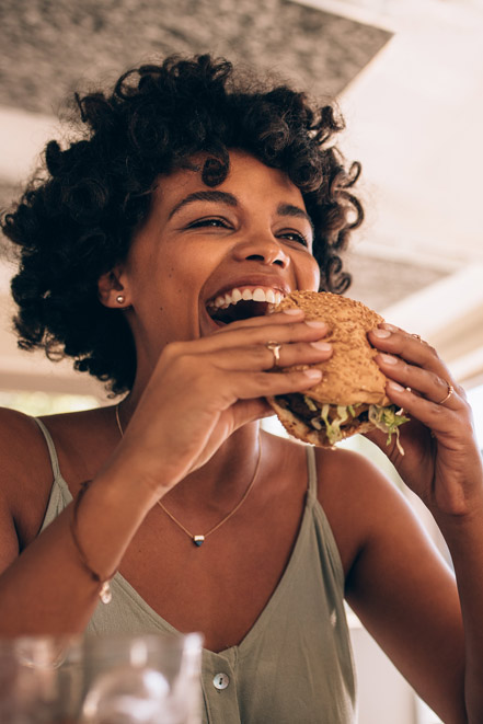 Woman laughing biting into hamburger