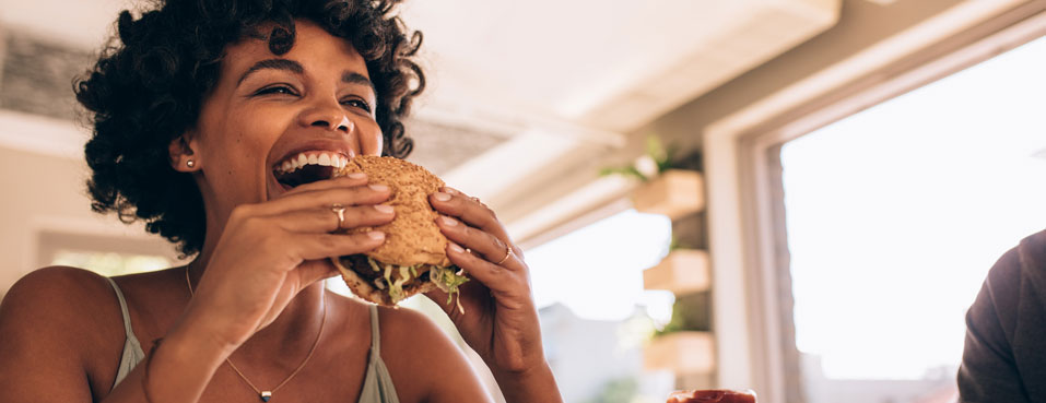 Laughing woman about to bite into hamburger