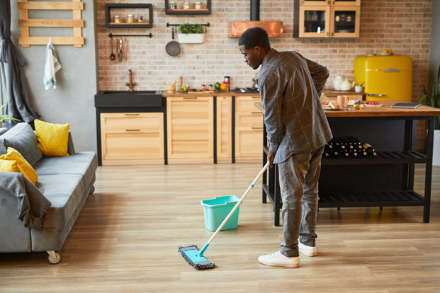 Dinner Date Full view of a young man mopping a floor in an apartment