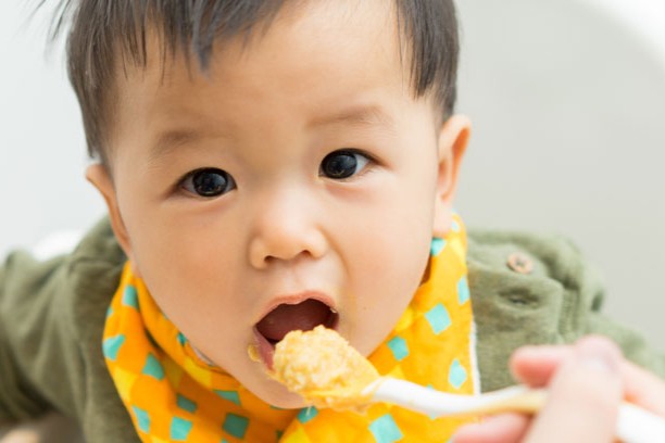 baby boy eating blend food on a high chair